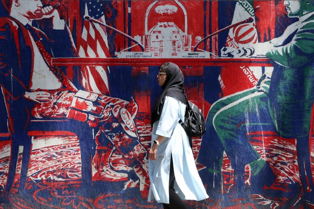 An Iranian woman walks past an anti-US mural, depicting an Iranian and US negotiation table, next to the former US embassy in Tehran, Iran, on June 22. Photo: EPA
