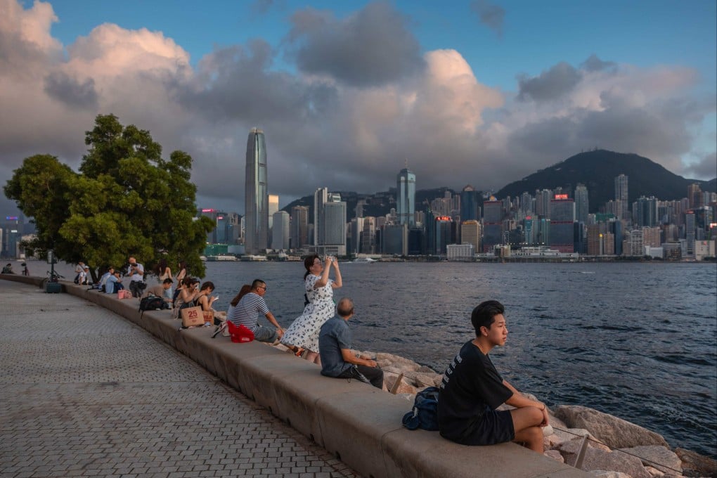 People sit on a promenade along Victoria Harbour in Hong Kong on June 23. Photo: AFP