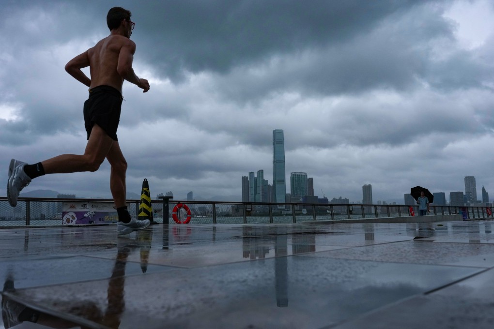 A jogger runs along the Sai Ying Pun waterfront as dark clouds loom over the Hong Kong skyline. Photo: Karma Lo