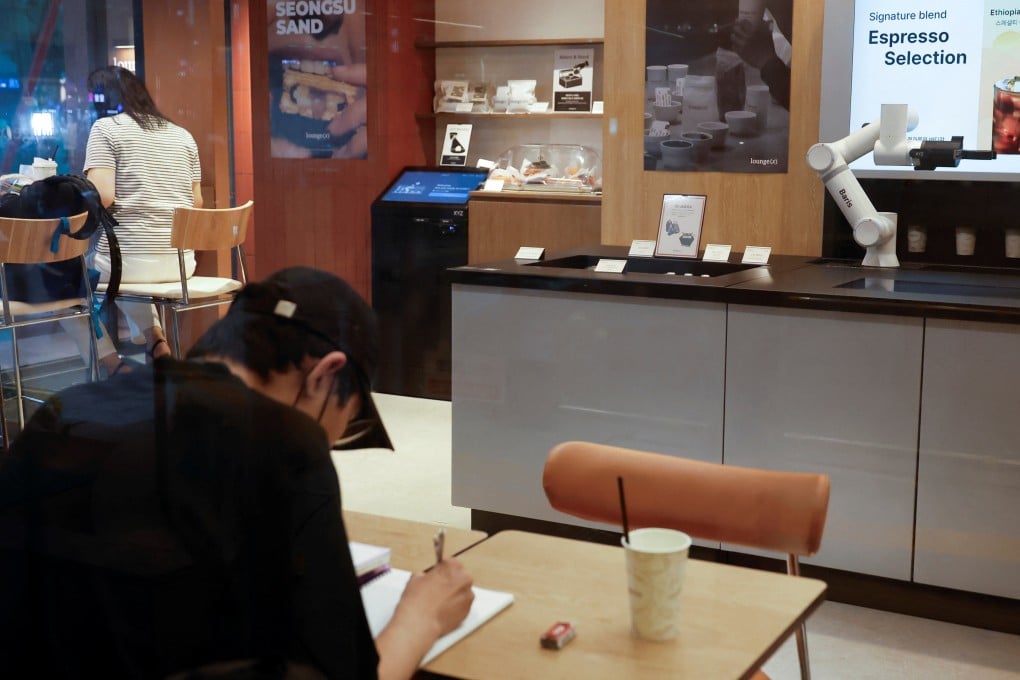 People sit inside an unstaffed cafe where a robot arm prepares coffee in Seoul on June 19. Photo: Reuters