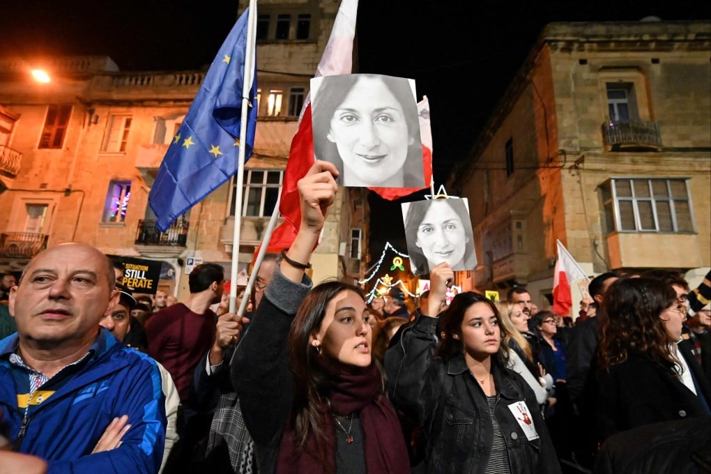 People hold placards and photos of slain journalist Daphne Caruana Galizia during a protest outside police headquarters in Valletta in December 2019. Photo: AFP
