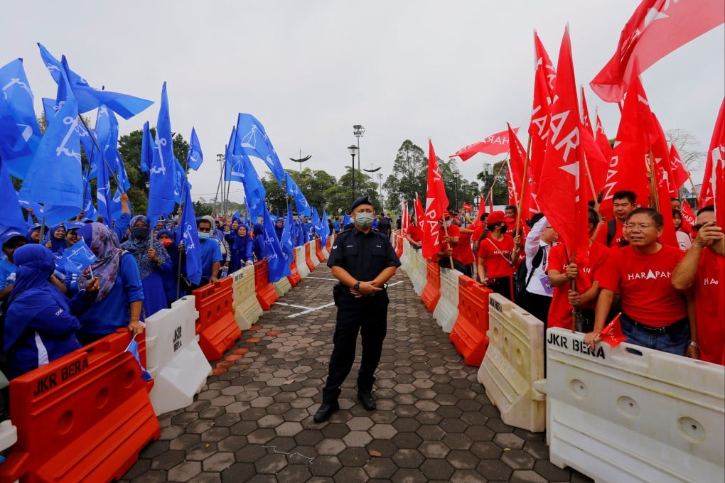 A police stands guard between supporters of Barisan Nasional and Pakatan Harapan in Malaysia in 2022. Photo: Reuters