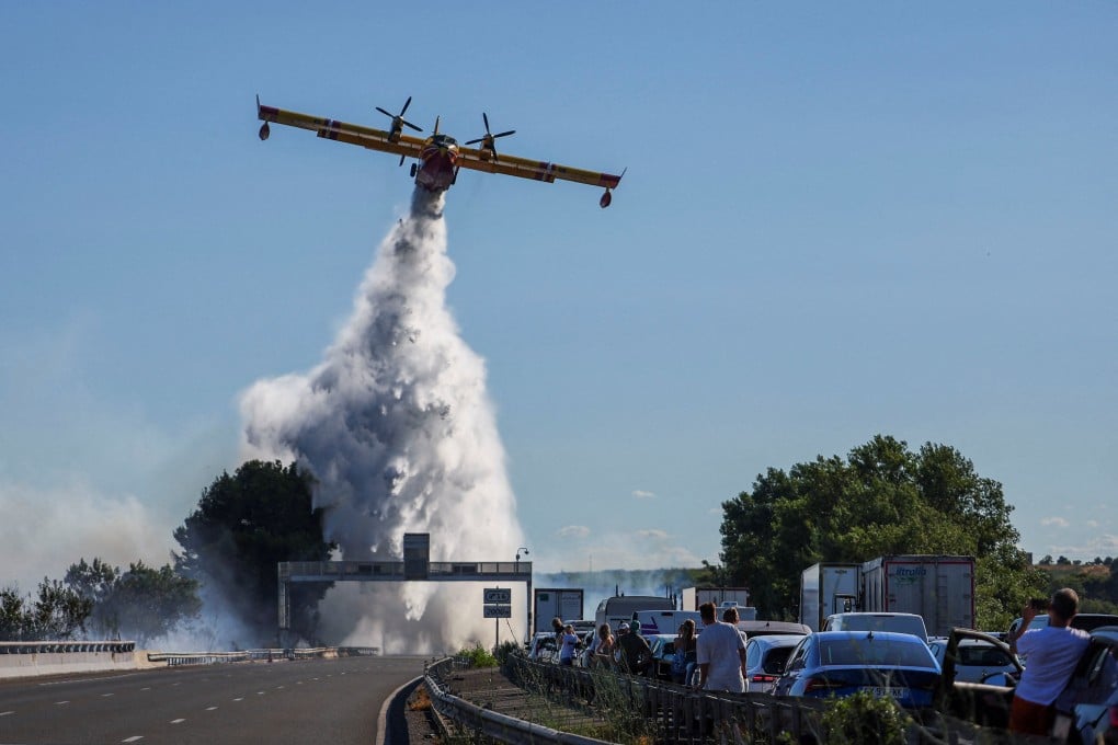 People watch as a firefighting plane tries to battle a wildfire by a motorway near Beziers, France, on Friday. Photo: Reuters