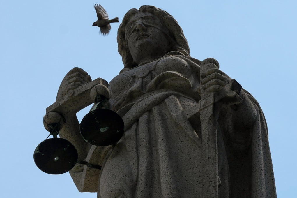 A sparrow flies above the statue of Themis, the blindfolded goddess of justice, perched on the roof of the Court of Final Appeal building in Central, Hong Kong, on March 13. Photo: Jelly Tse