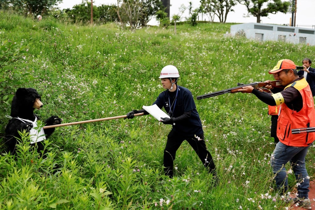 A participant checks for signs of life in a stuffed bear representing a real animal while a hunter stands ready during an emergency response drill in Isehara, Kanagawa prefecture, on Friday. Photo: Reuters