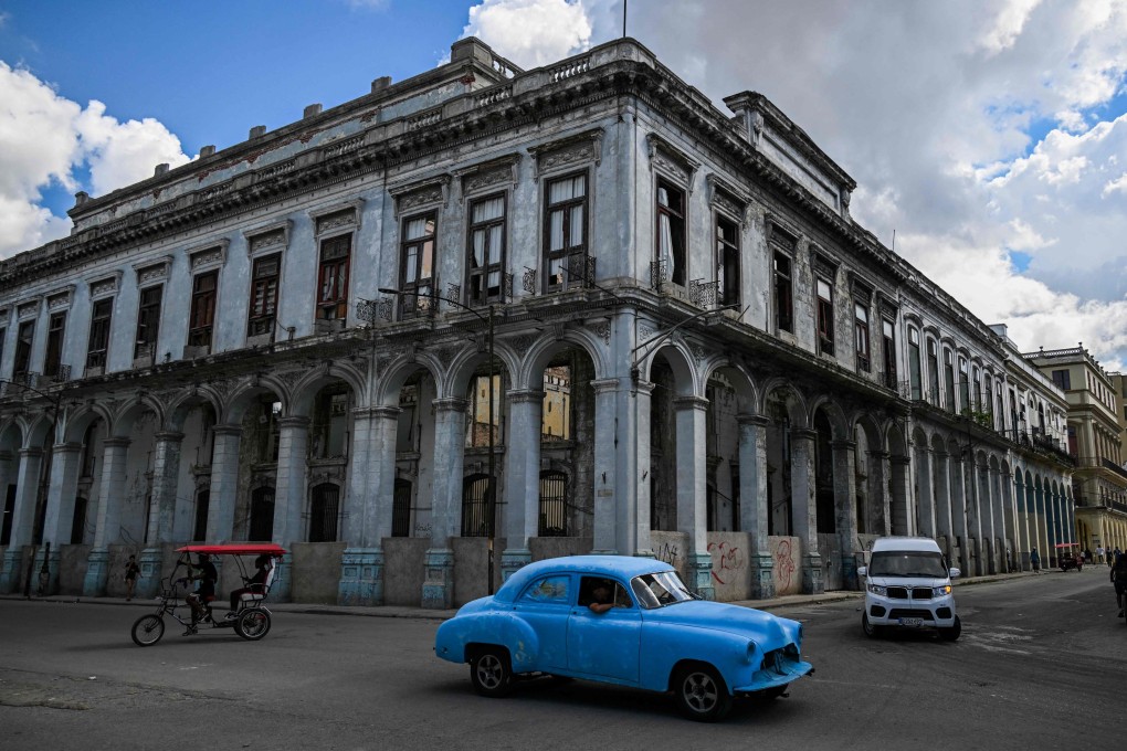 An old US car drives past a building at risk of collapse in Havana. Photo: AFP