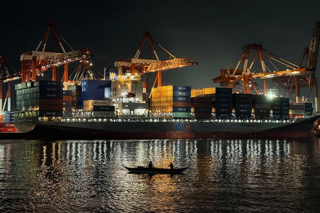 Fishermen paddle past a cargo ship unloading containers at the Manila international port in the Philippines in December 2025. Photo: AFP
