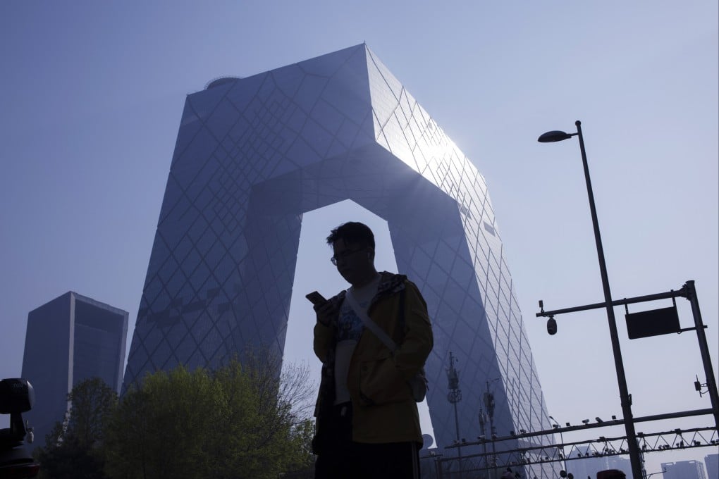 A man checks his phone while walking in Beijing’s central business district. Photo: EPA-EFE