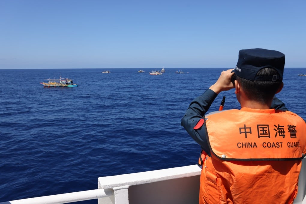 A China Coast Guard crew member observes Philippine vessels in the disputed South China Sea. Photo: Handout via Xinhua