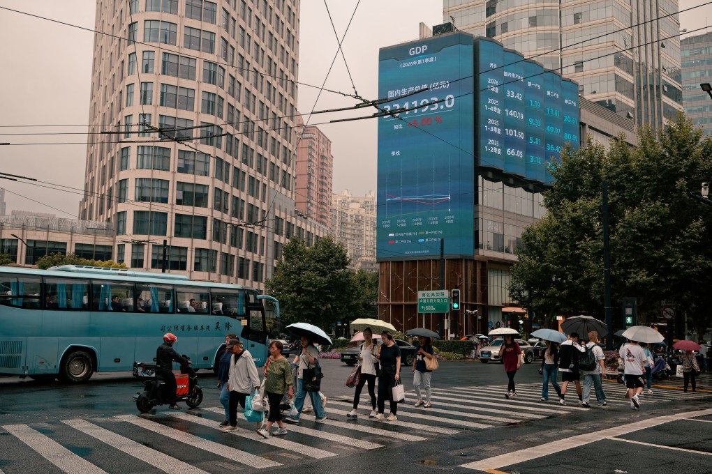 People walk on a street beneath a screen showing stock market and economic data in Shanghai on June 15. Photo: EPA