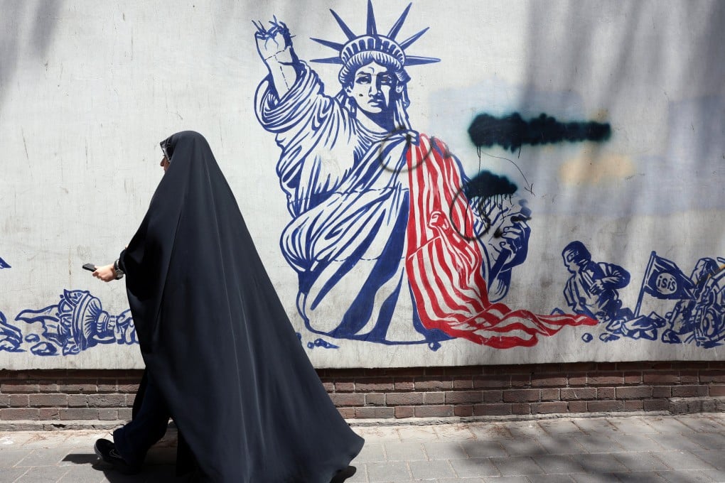 A woman walks past an anti-US mural next to the former US embassy in Tehran on Thursday. Photo: EPA