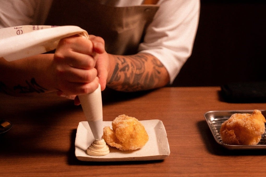 Dominic Li of Dom squeezes out a portion of the restaurant’s yin yang milk tea cream to accompany its deep fried souffle egg white. The Cantonese fine dining restaurant is located in Melbourne’s Southbank neighbourhood. Photo: Instagram/domsouthbank