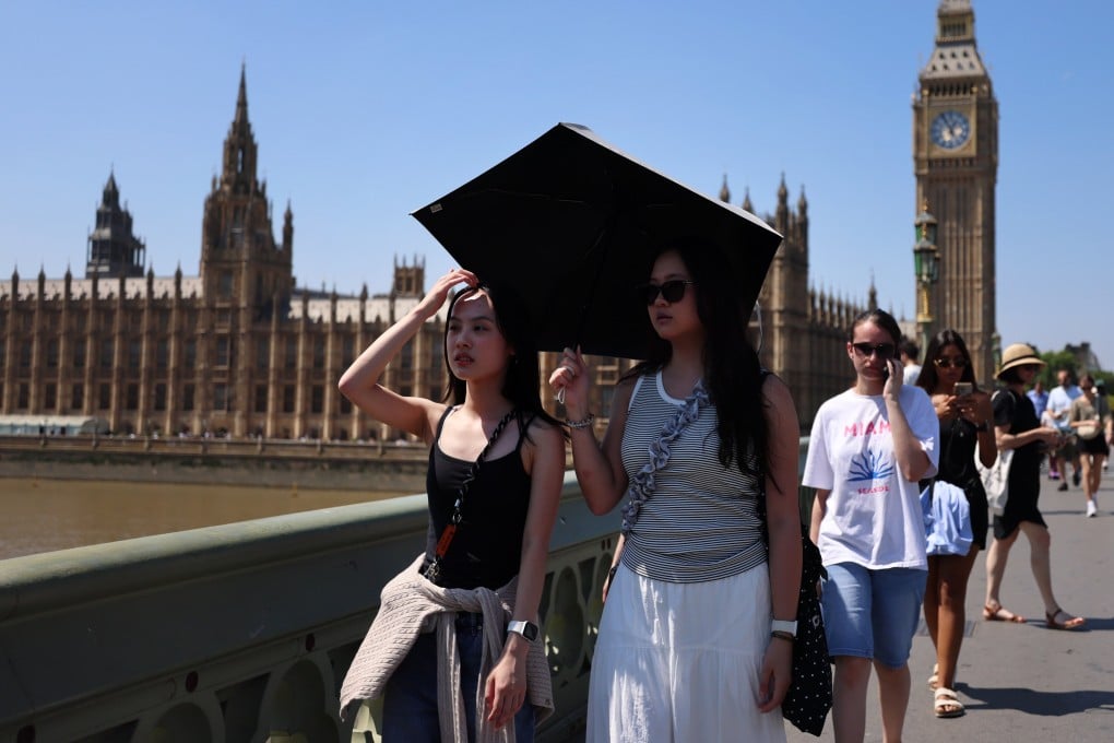 People shelter from the sun while walking across Westminster Bridge in London, Britain as the UK braces for one of the longest-lasting heatwaves in 50 years. Photo: EPA