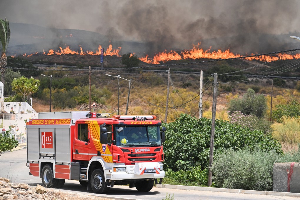 A firefighting vehicle drives by as smoke and flames rise during deadly wildfires affecting Almeria province in Alfaix, Spain, on July 10. Photo: Reuters