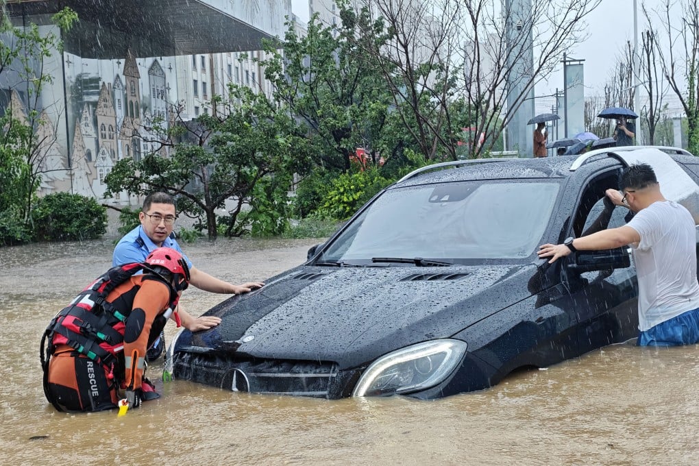 A police officer and firefighter help a driver whose car was stranded by the heavy rains in Shenyang, provincial capital of Liaoning in northeast China. Photo: Xinhua