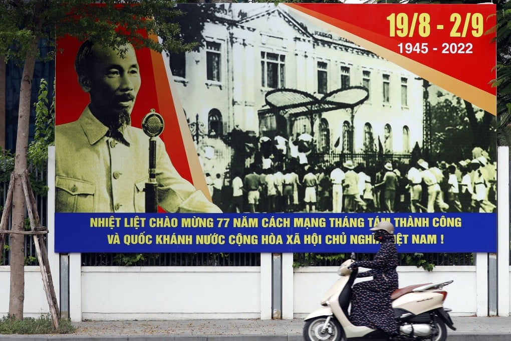 A woman rides a motorbike past a poster with a portrait of the late former president Ho Chi Minh in Hanoi on August 31, 2022. Photo: EPA-EFE