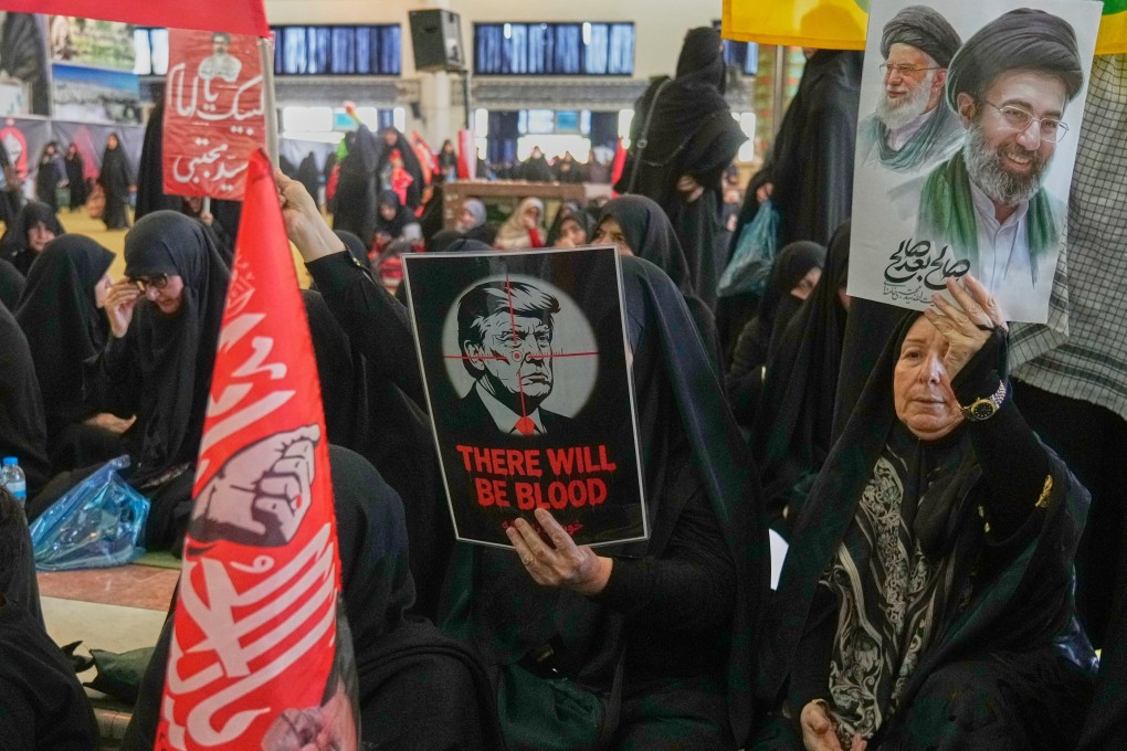 A woman in Tehran holds a poster depicting US President Donald Trump in crosshairs. Photo: AP