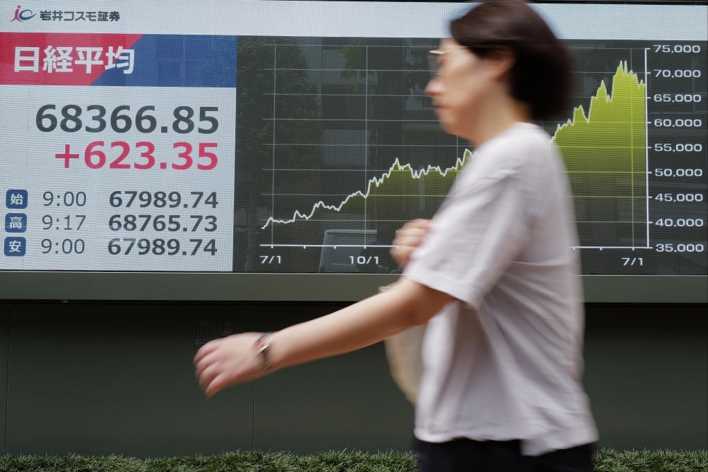 A woman walks in front of an electronic stock board showing Japan’s Nikkei 225 index at a securities firm in Tokyo on July 15. Photo: AP