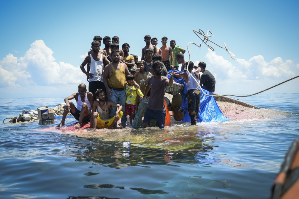 Rohingya refugees stand on their capsized boat as rescuers throw a rope to them off West Aceh, Indonesia, in 2024. Photo: AP