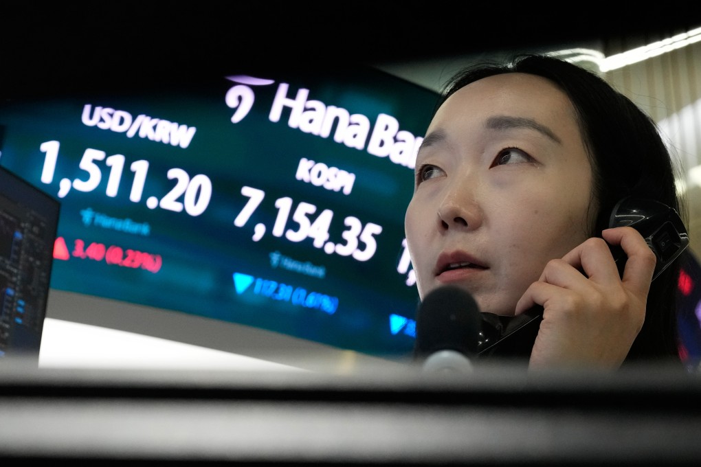 A currency trader talks on the phone near a screen showing the Korea Composite Stock Price Index (Kospi) and US dollar exchange rate  in Seoul. Photo: AP
