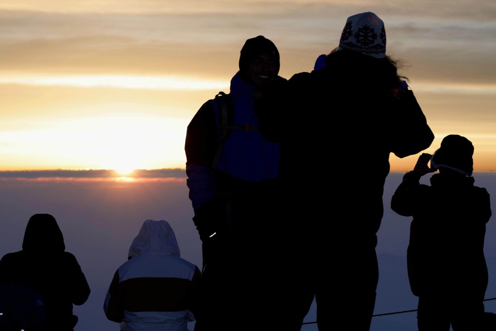 People take photos of the sunrise atop Mount Fuji on July 1, the first day of the official climbing season for Japan’s highest mountain. Photo: Kyodo