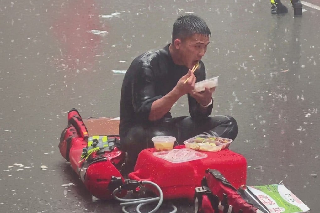 Guangdong firefighter, Liang Huan, grabs a quick meal in the pouring rain during severe flood relief operations in Guangxi. Photo: 163.com