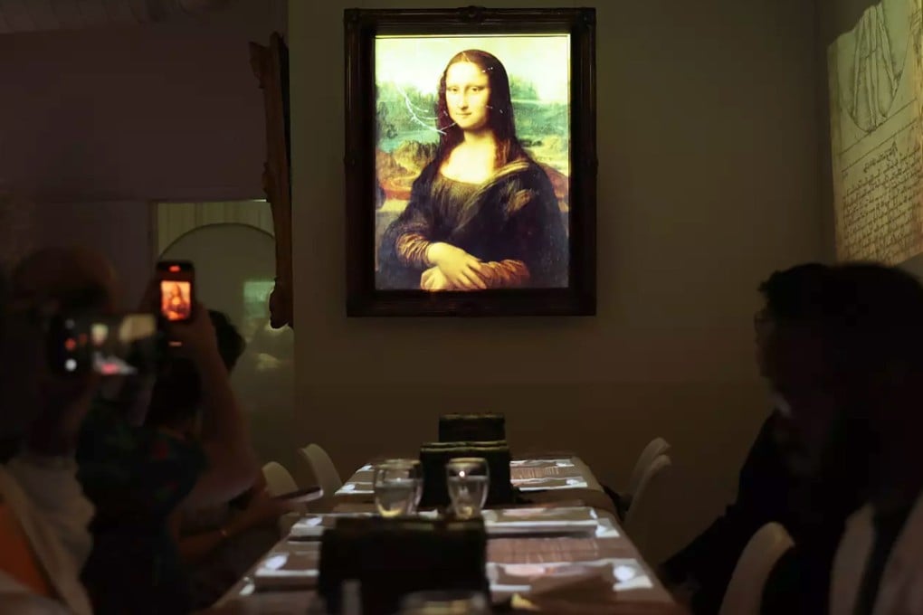 An animated Mona Lisa hangs beside a dining table during a 7 Paintings experience in Los Angeles, where guests learn about fine art. Immersive dinners incorporating advanced multimedia technology are trending from the US to Europe and Asia. Photo: Los Angeles Times/TNS