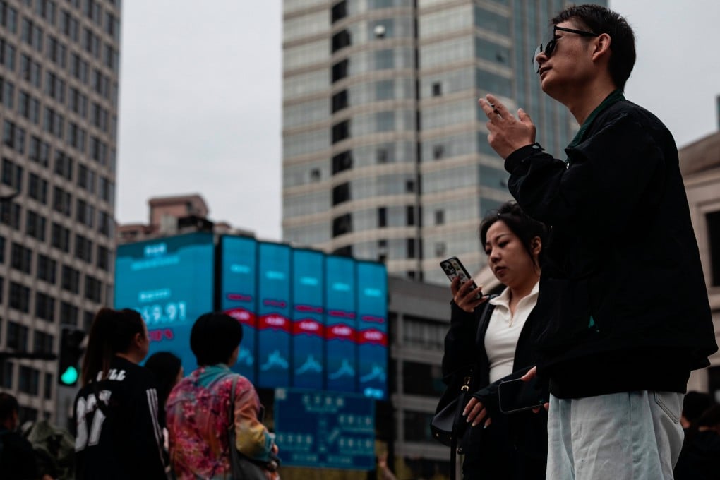 People cross the street beneath a large screen showing the latest stock exchange data in Shanghai on April 8. Photo: EPA
