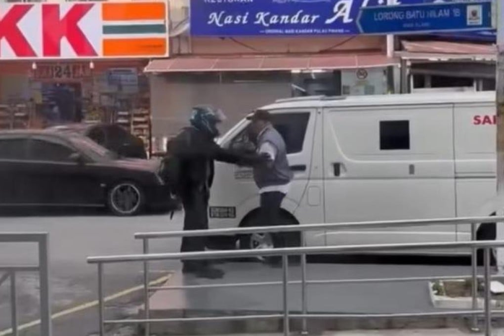 A screengrab shows a robber holding up a security guard outside a bank in Klang on Monday. Photo: Instagram/suaramalaysiabaru