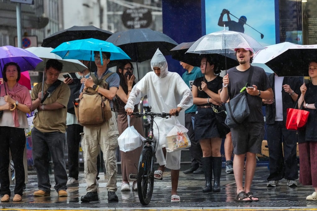 People wait to cross the road in Tsim Sha Tsui during heavy rain on July 16. For delivery workers and part-timers, income is tied directly to hours worked and work suspensions during extreme weather can mean immediate financial hardship. Photo: Jelly Tse