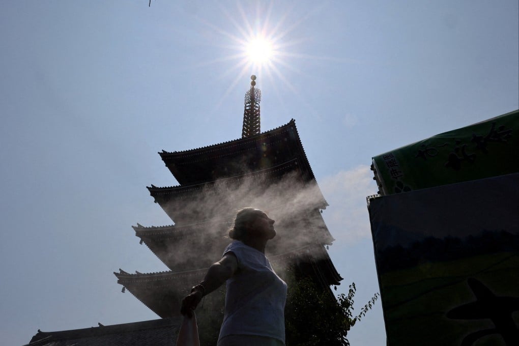 A visitor stands next to a cooling mist at Sensoji temple in Tokyo on Wednesday. Photo: Reuters