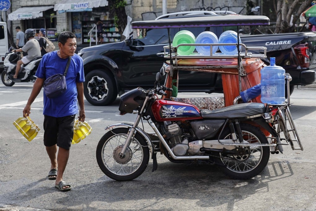 A vendor carries bottles of cooking oil to sell at a market in Quezon City, the Philippines, on July 7. Photo: EPA
