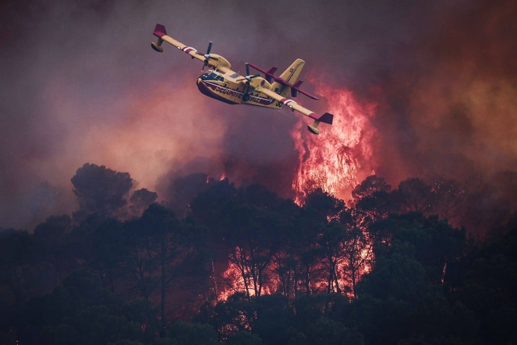 A French Civil Security Canadair CL-415 aircraft flies past flames burning a forest surrounding Cotignac, southeastern France, on Thursday. Photo: AFP