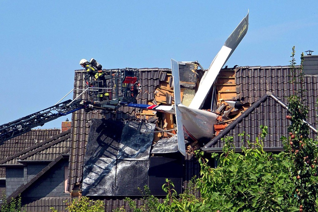 A small plane that crashed is lodged in the roof of a house in Ganderkesee, Germany. Photo: dpa