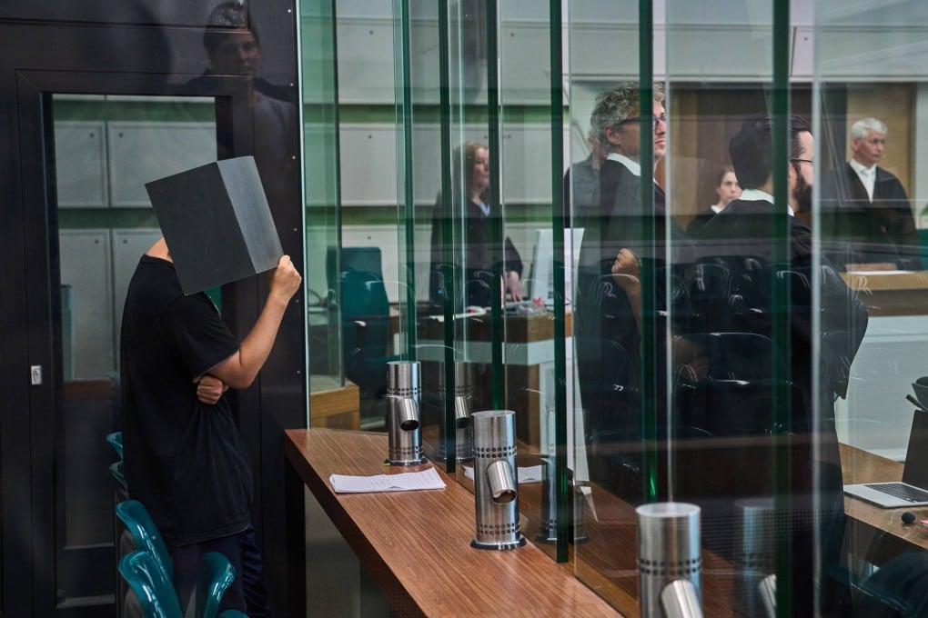A Chinese doctor, pictured covering his face, has been jailed for five years by a Berlin court over aiding and abetting aggravated rape and sexual coercion. Photo: AP