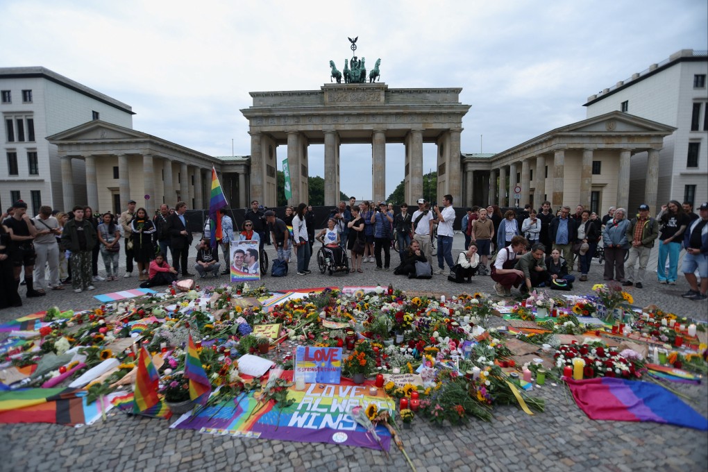 People gather around flowers, mementos and candles left by people at Berlin’s Brandenburg Gate on Sunday after a car ramming near Berlin’s annual Christopher Street Day Pride parade on Saturday. Photo: Reuters