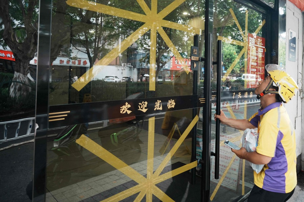 A food delivery man opens a door with taped glass at a restaurant in Hangzhou, eastern Zhejiang province , as people prepare for the approaching Typhoon Bavi to hit the region on July 11, 2026. Photo: AFP