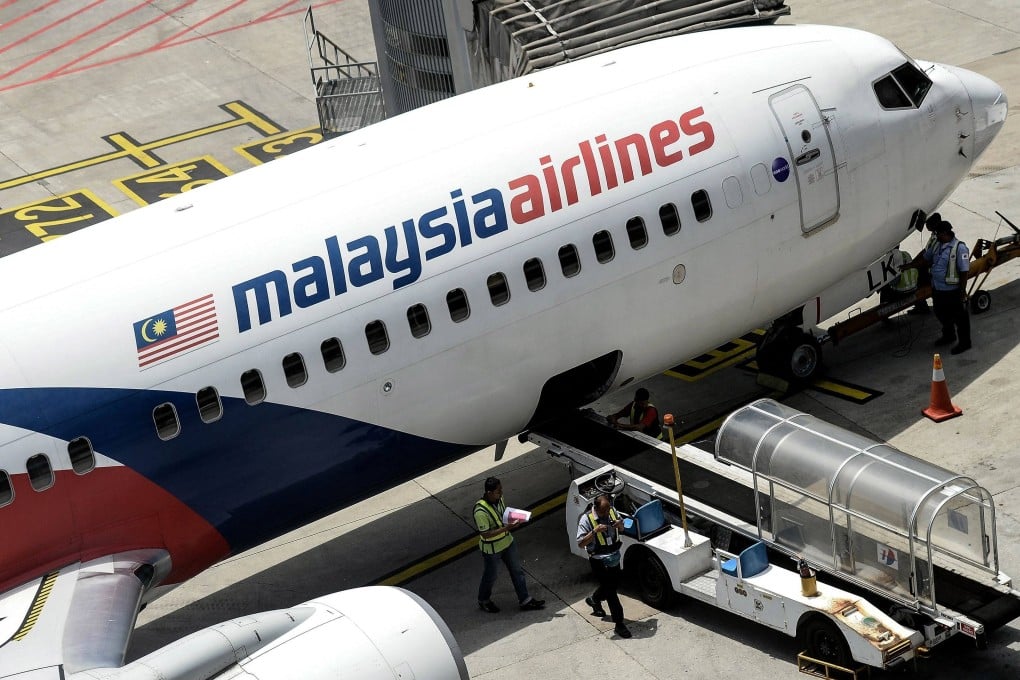 Malaysia Airlines ground staff walk on the tarmac next to a Malaysia Airlines plane at Kuala Lumpur International Airport. Photo: AFP