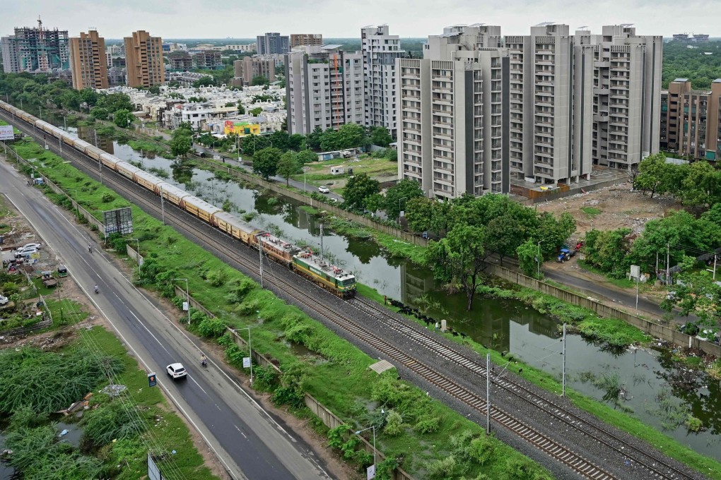 A train runs along a residential neighbourhood as monsoon clouds hover in Ahmedabad in the Indian state of Gujarat on August 1. Photo: AFP