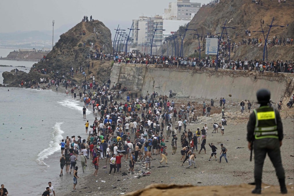 People gather along the fence at the site of clashes near Fnideq, on the Morocco-Spain border, on Friday. Photo: AFP