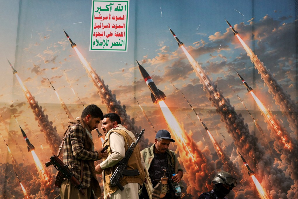 Armed Houthi supporters stand before a banner depicting missiles in Sanaa, Yemen. Photo: Reuters