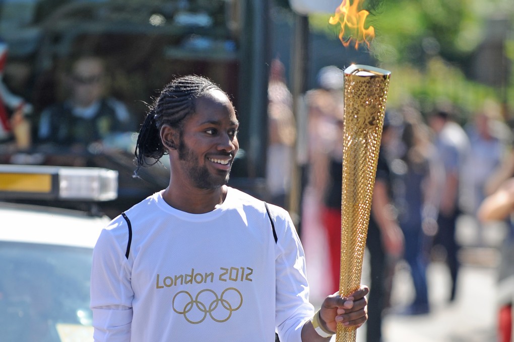 Jason Arday carries the Olympic Flame in London in July 2012. Photo: PA via AP
