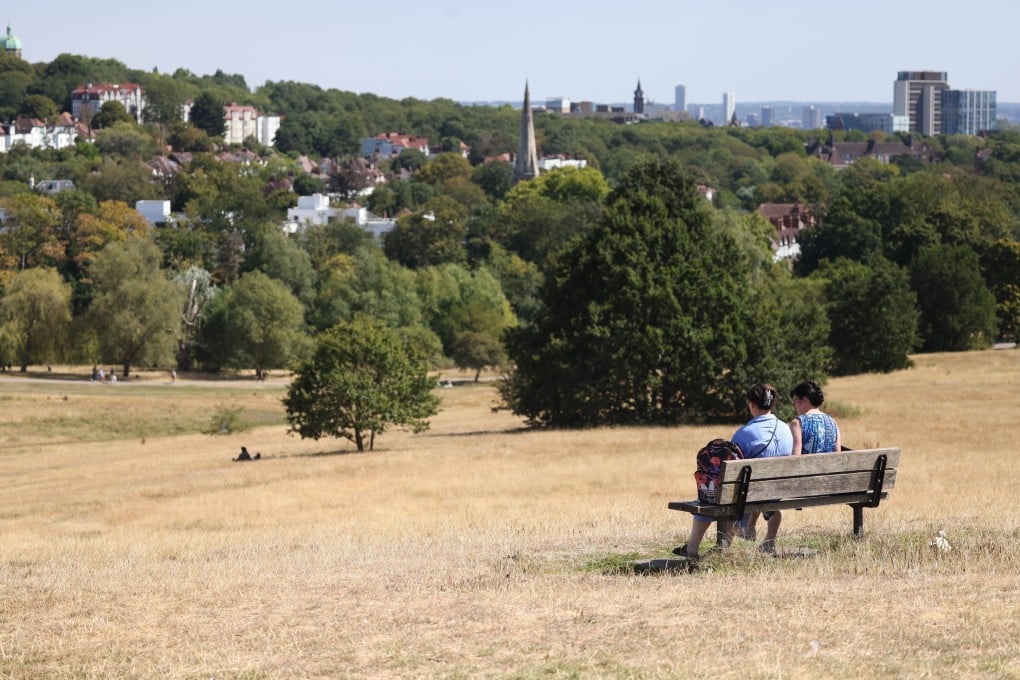People sit on a bench in dry grass at Hampstead Heath in London, Britain, on Sunday. Photo: EPA