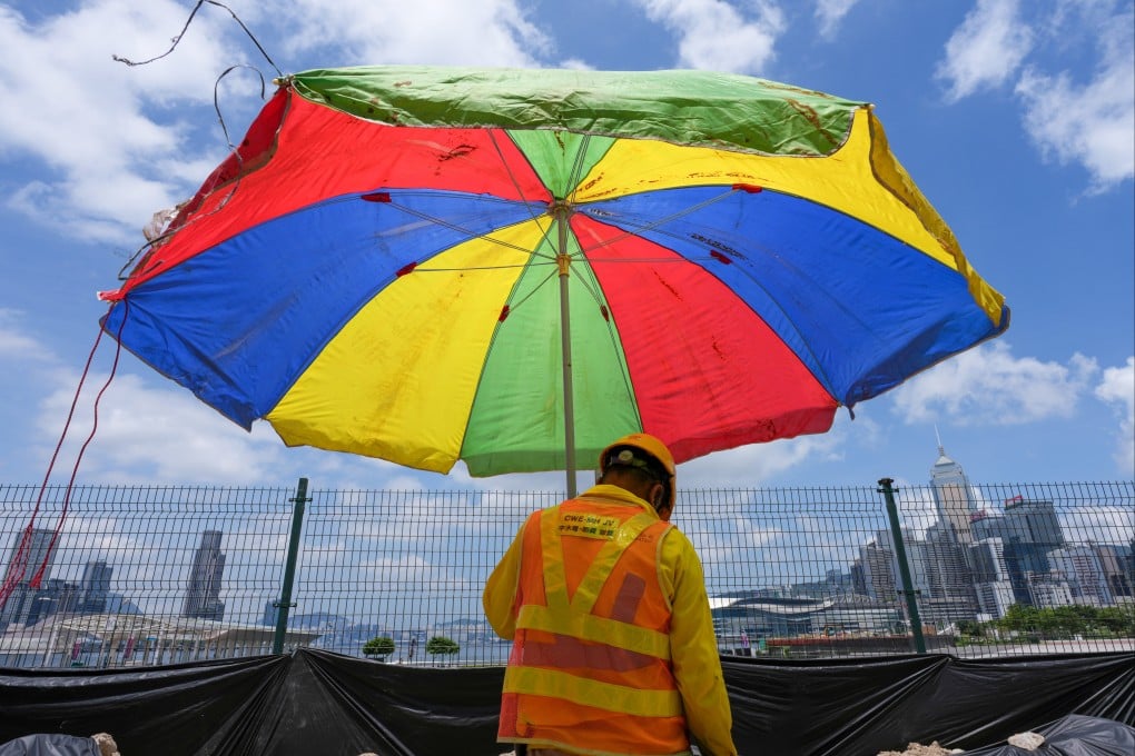 A construction worker shelters under an umbrella in Central. Photo: Karma Lo