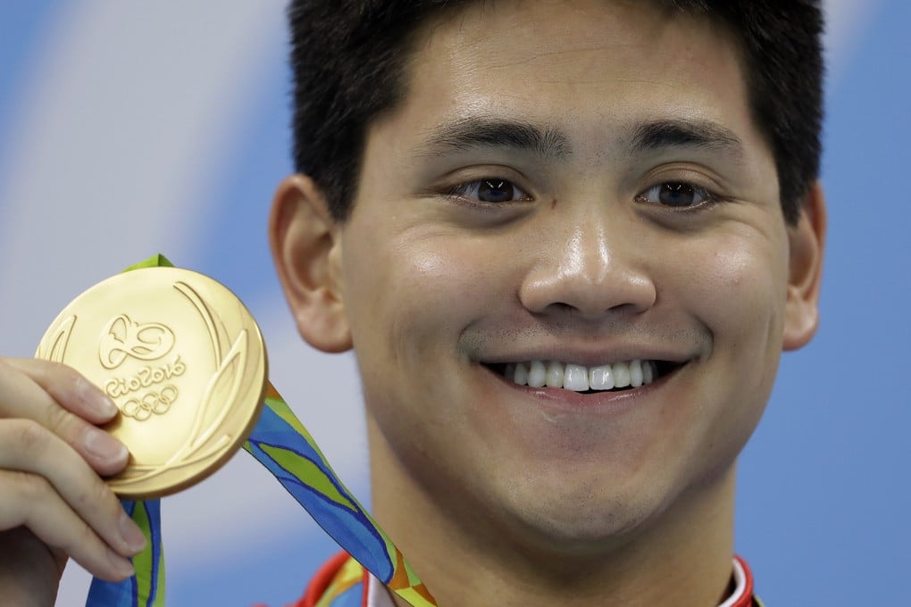 Singapore’s Joseph Schooling shows off his gold medal in the men’s 100-meter butterfly medals ceremony during the swimming competitions at the 2016 Olympics on August 12, 2016. Photo: AP