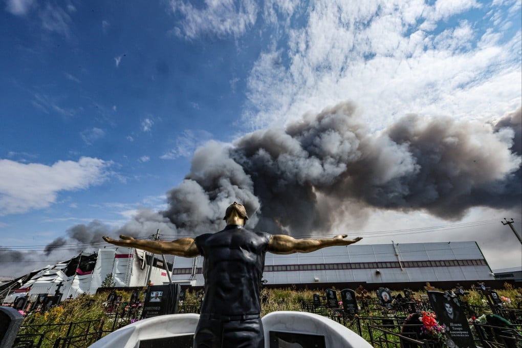 A grave sculpture at a cemetery as smoke rises in the background above a Wildberries facility, following a reported Ukrainian drone strike at the Koledino Industrial Park near Podolsk, Moscow Region, Russia, on Sunday. Photo: EPA-EFE