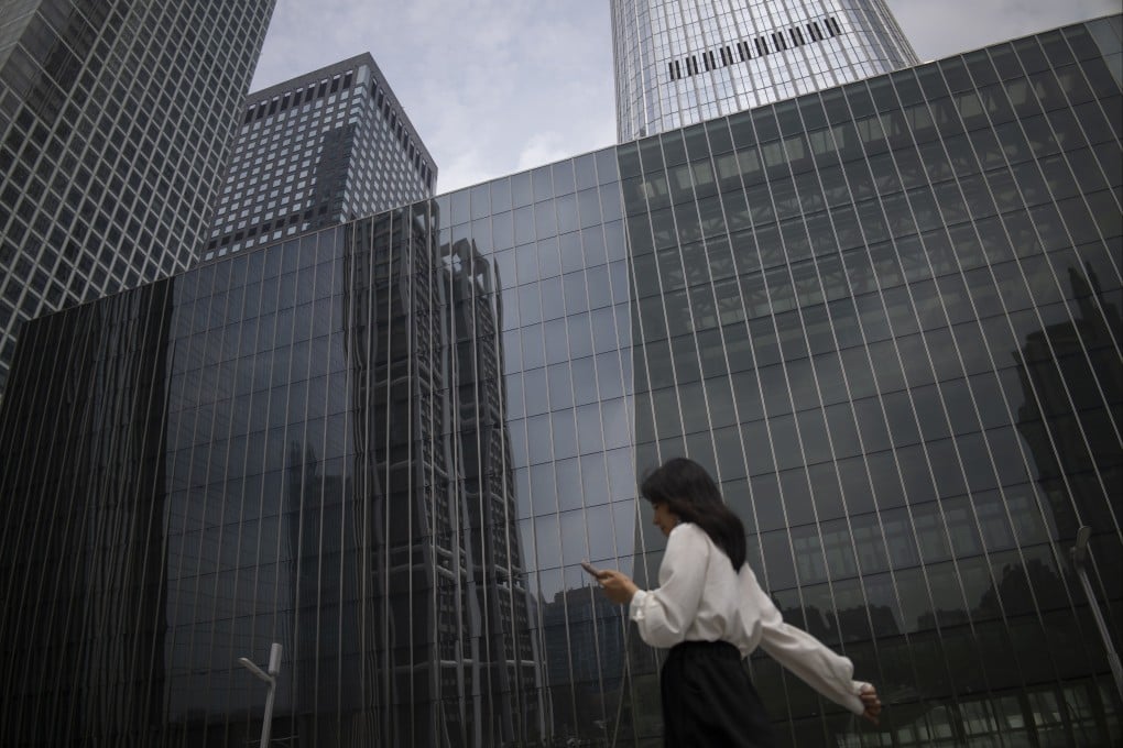 A woman walks past a row of buildings in Beijing’s central business district on July 31. Photo: EPA