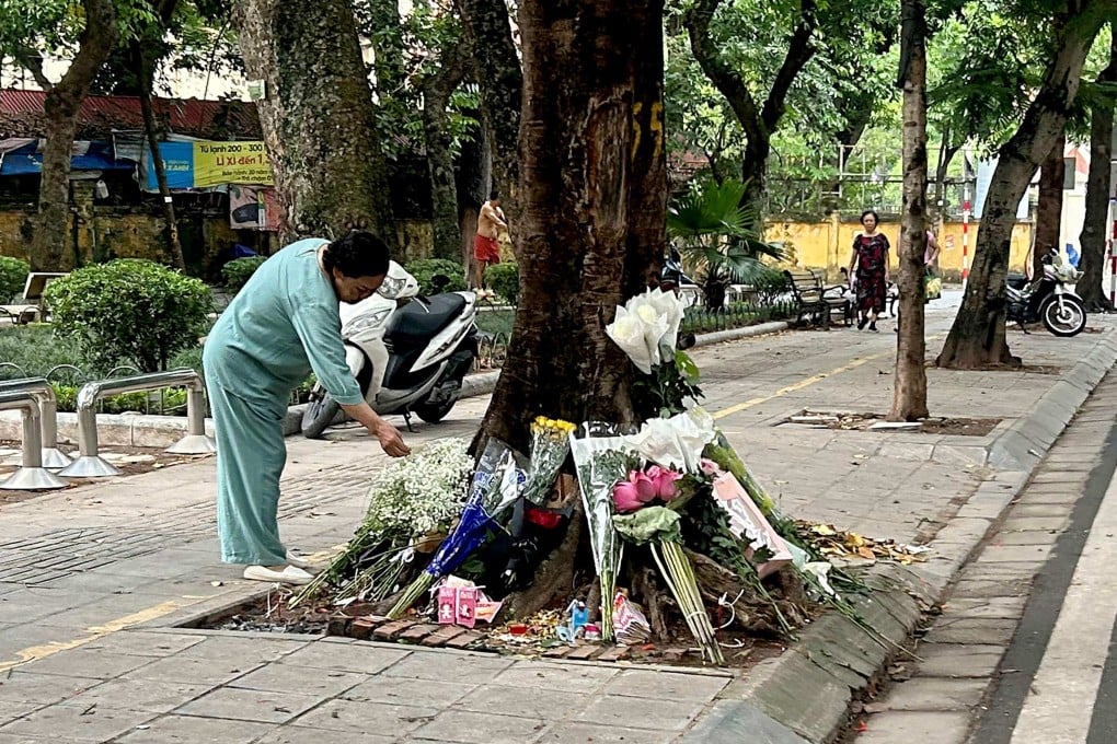 A woman looks at flowers placed on Saturday at the site of a traffic accident where a senior official had a fatal car crash in Hanoi. Photo: AFP
