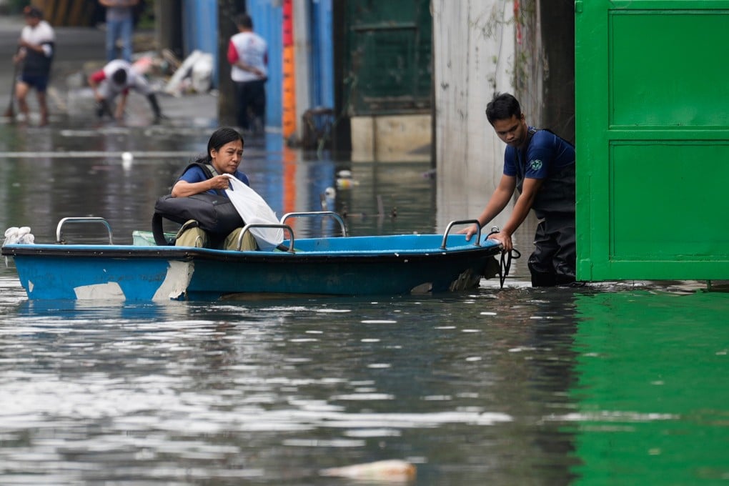 A woman rides a small boat to cross floodwaters caused by intense monsoon rains in Quezon City, Metro Manila, Philippines, on Wednesday. Photo: AP