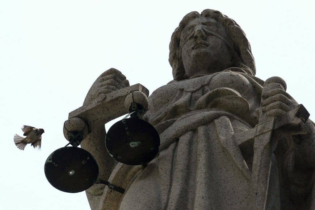 A sparrow flies near the statue of Themis, the blindfolded goddess of justice, on the roof of the Court of Final Appeal building in Central. Photo: Jelly Tse